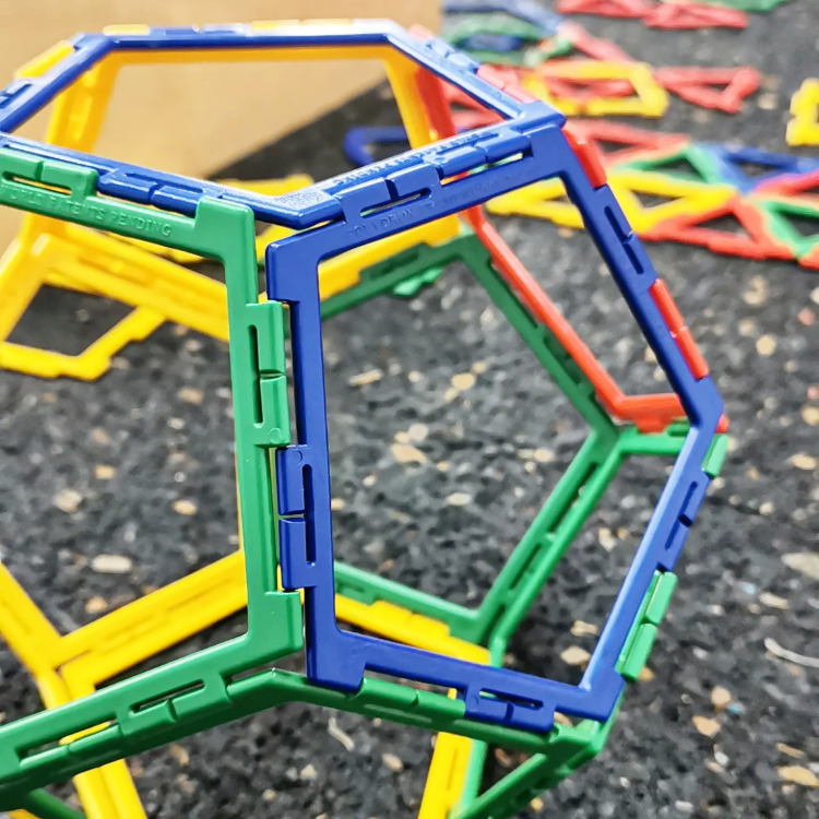 Bunte dreidimensionale geometrische Formen aus Kunststoffstäben auf dunklem Untergrund,