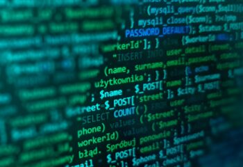 Bildschirm mit grünem und blauem Programmiercode auf schwarzem Hintergrund, zeigt SQL-Befehle und Variablen