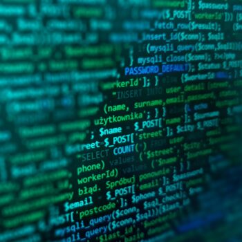 Bildschirm mit grünem und blauem Programmiercode auf schwarzem Hintergrund, zeigt SQL-Befehle und Variablen