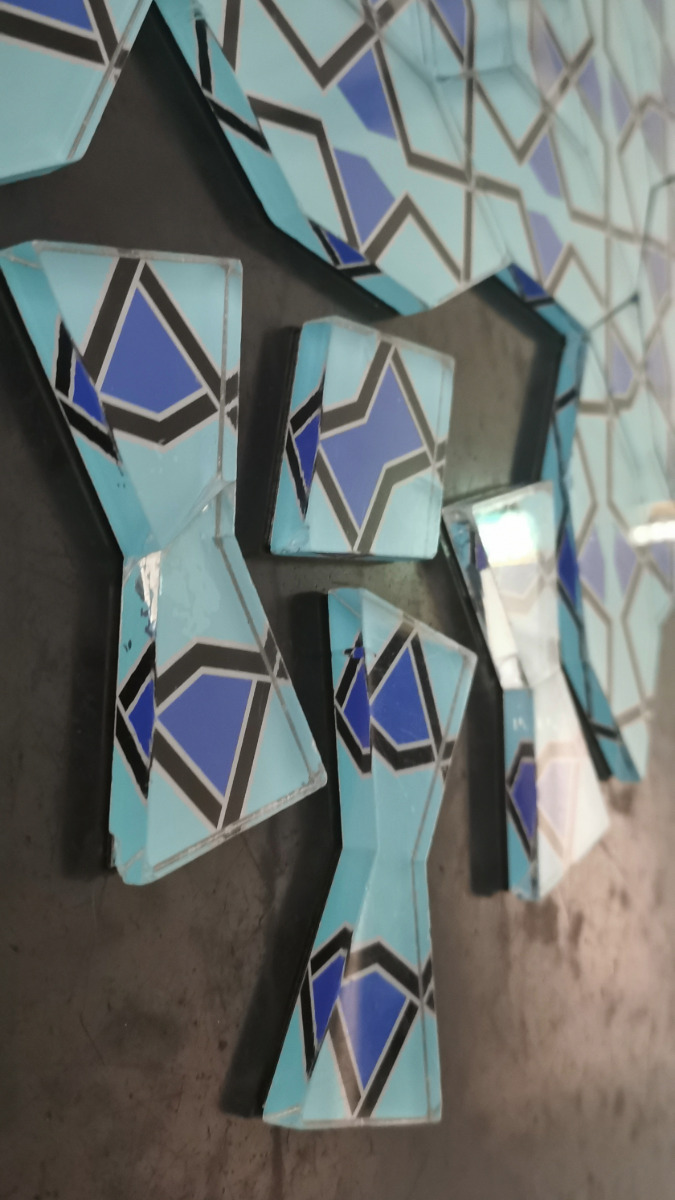 Nahaufnahme von blauen, schwarz-weißen Fliesen mit geometrischem Muster auf dunklem Untergrund